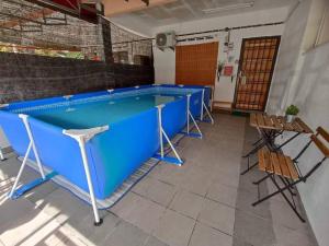 uma piscina num quarto com cadeiras e uma mesa em Basrie Homestay Pagoh - Private Pool/W-ifi/NetFlix/Cozy em Pagoh