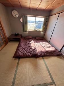 1 cama en un dormitorio con reloj en la pared en SUN庭園 en Himeji