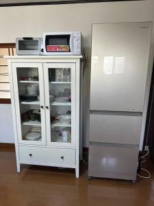 um armário branco com um micro-ondas e um frigorífico em SUN庭園 em Himeji