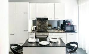 cocina con armarios blancos y encimera negra en La Casa - comfortable - by PA, en Lucerna
