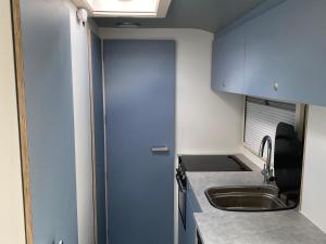 a small kitchen with a sink and a blue door at Hall Farm Hideaway in Kings Lynn