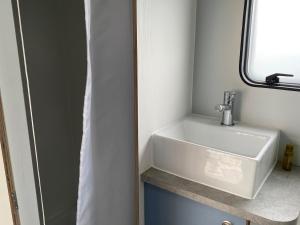 a white sink in a bathroom with a window at Hall Farm Hideaway in King's Lynn