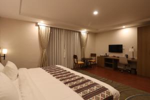 Habitación de hotel con cama, escritorio y TV. en Thimphu Deluxe Hotel en Thimphu