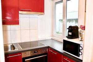 a kitchen with red cabinets and a sink and a microwave at Lucerne Apartment - near lion monument - by PAF in Lucerne