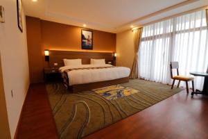 ein Hotelzimmer mit einem Bett und einem großen Fenster in der Unterkunft Thimphu Deluxe Hotel in Thimphu