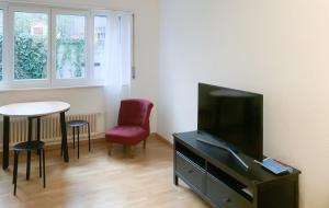 - un salon avec une télévision, une table et des chaises dans l'établissement Lucerne Apartment - near lion monument - by PAF, à Lucerne