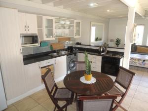 a kitchen with a table and chairs and a kitchen with a sink at No 1 @ The Dunes in Plettenberg Bay