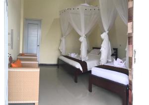 a bedroom with two beds and a canopy bed at jaya hill garden in Kelimutu