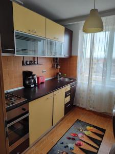 une cuisine avec des armoires jaunes, un évier et un tapis dans l'établissement HMM Apartament, à Sibiu