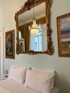 1 dormitorio con espejo y 1 cama con almohadas blancas en B&B Art Suite Santa Brigida, en Nápoles