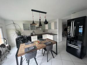 a kitchen with a wooden table and a black refrigerator at Gîte des hirondelles - Appartement de 75 m2 in Évette