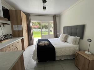 a bedroom with a large bed and a kitchen at VIilla Vredenrust Guesthouse in Bloemfontein
