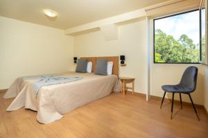 a bedroom with a bed and a chair and a window at Spacious House with Pool in Prazeres in Prazeres +20 photos