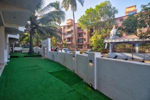 a fence with green grass in front of a building at Pajaros Blu in Calangute