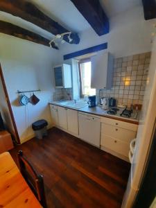 eine Küche mit weißen Schränken und Holzböden in der Unterkunft Lou Cantou in Marnac