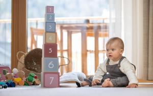 ein Baby auf dem Boden neben einem Spielzeugblock in der Unterkunft das bleibt Alpine Suites in Schladming