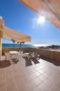 a patio with a table and chairs and an umbrella at CARIHUELA 1ª LÍNEA DE PLAYA in Torremolinos
