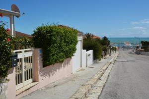 una strada vuota vicino a una recinzione bianca e all'oceano di La casa di Lillo a Marina di Ragusa