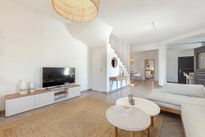 un soggiorno con divano bianco e TV di Escape View Villa with private pool by Caldera Houses a Éxo Goniá
