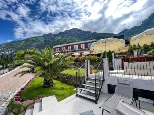 a balcony with a palm tree and a building at Hotel Oasi Beach in Malcesine