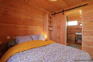 um quarto com uma cama num chalé de madeira em LA CABANE DE JABI em Trémont
