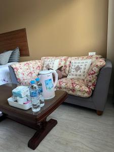 Better Life Residence Phuket في شاطئ ناي يانغ: غرفة معيشة مع أريكة وطاولة مع زجاجات المياه