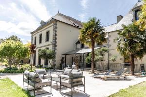 une maison avec une terrasse et des chaises en face de celle-ci dans l'établissement Manoir des Indes, The Originals Relais (Relais du Silence), à Quimper