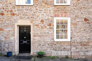 een stenen gebouw met een zwarte deur en twee ramen bij Fabulous 2 bedroom cottage in fantastic Clifton - Simply Check In in Bristol