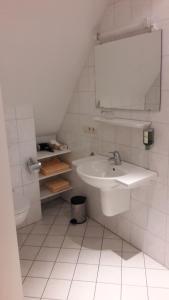 La salle de bains blanche est pourvue d'un lavabo et d'un miroir. dans l'établissement Landhaus Lastrup, à Lastrup