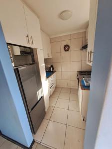 a small kitchen with a refrigerator and a tiled floor at Madeira House in Cape Town