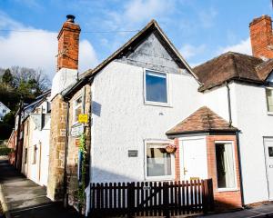 a white house with a black fence in front of it at Thursdays Corner Tudor Cottage in Church Stretton