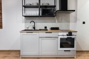 una cucina con armadi bianchi, lavandino e forno a microonde di Dream Aparts - Piotrkowska 152 Select a Łódź