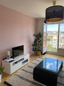 un soggiorno con TV e tavolo in vetro di T3 Hypercentre-dernier étage-Balcon-Garage-Queen beds-vue panoramique a Saint-Étienne