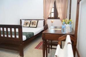 a bedroom with a bed and a desk and a table at Muduna Walawwa Resort in Kandy