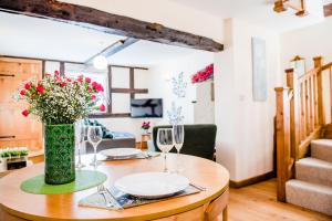 a table with a vase of flowers and wine glasses at Thursdays Corner Tudor Cottage in Church Stretton
