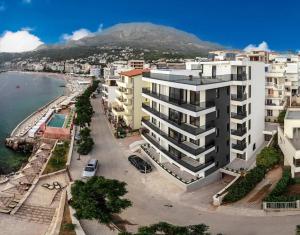 a large white building next to a beach with buildings at Kalamper Apartments in Dobra Voda