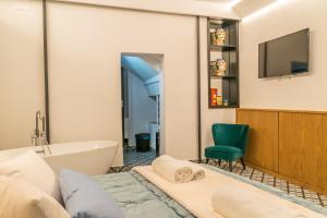 a bathroom with a tub and a television and a bed at Community Rooms & Wine in Favara