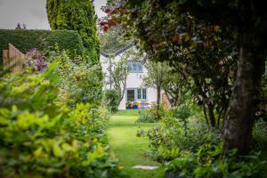 um jardim com uma casa branca e alguns arbustos em Gamekeeper's Cottage em Dorchester