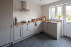 a kitchen with white cabinets and a sink and a window at Gamekeeper's Cottage in Dorchester
