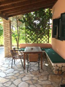 a patio with a table and chairs and a bench at ARISTIDIS Apartments in Lefkimmi