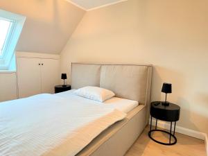 韋斯特蘭的住宿－Dünen Lodge，一间卧室配有一张带两盏灯的大型白色床。