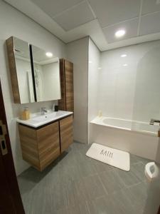 a bathroom with a sink and a tub and a bath mat at Modish Classy Apartment In Jumeirah in Dubai