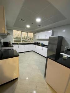 a large kitchen with white cabinets and black counter tops at Modish Classy Apartment In Jumeirah in Dubai