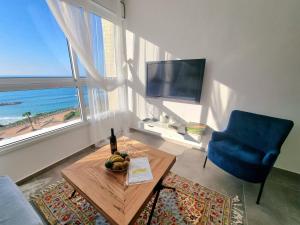 salon ze stołem i niebieskim krzesłem w obiekcie Beautiful 2-Bedroom Sea-View apartment w mieście Netanja