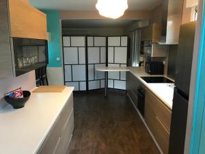 a kitchen with white counters and wooden cabinets at Saint-Avertin Maison la Tourangelle à partager en famille ou amis in Saint-Avertin