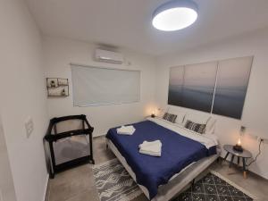 sypialnia z dużym łóżkiem i niebieskim kocem w obiekcie Beautiful 2-Bedroom Sea-View apartment w mieście Netanja