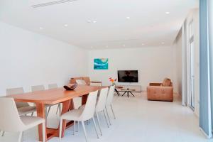 a dining room with a wooden table and white chairs at Sunrise Seaview Villas - Camelia in Paralimni