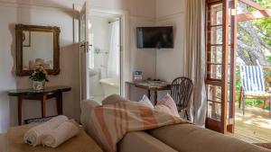 een woonkamer met een bank en een glazen schuifdeur bij Eastcliff Cottage in Hermanus