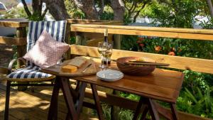a wooden table with a glass of wine and cheese at Eastcliff Cottage in Hermanus
