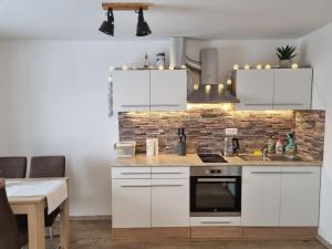 uma cozinha com armários brancos e uma parede de tijolos em Apartmán Felix em Vaclavov u Bruntalu